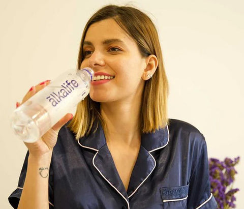 girl drinking a 600ml bottle of ãlkalife naturally alkaline mineral water